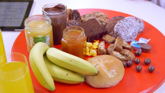 Bananen, Honig, Marmelade, Schokonusscreme, Kuchen, kekse, Süßigkeiten auf einem Teller. © NDR 