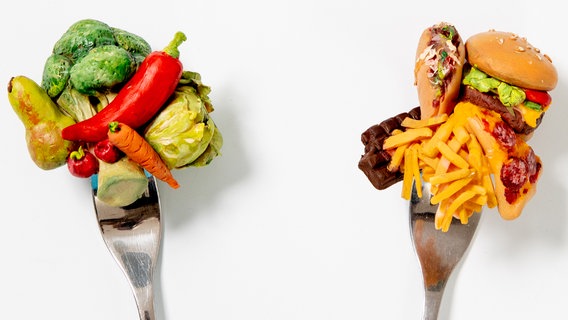 Zwei Gabeln: links mit buntem Gemüse, rechts mit Burger, Eis und Fritten. © NDR Foto: Claudia Timmann