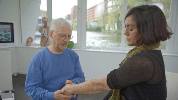 Dr. Klasen untersucht den Arm einer Patientin. © NDR 