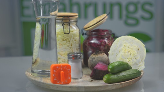 Eine Wasserkaraffe, Salz, Weißkohl, Rote Bete, Gurken und ein Einmachglas mit Kraut, dazu ein Küchenwecker. © NDR Foto: Moritz Schwarz/Oliver Zydek