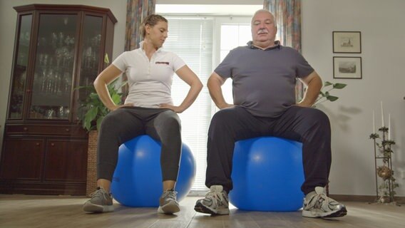 A physiotherapist and her patient are sitting on a ball © NDR 