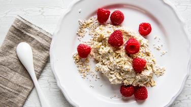 Teller mit Quark, Getreidekörner und Himbeeren, danaben ein Löffel. © NDR Foto: Claudia Timmann