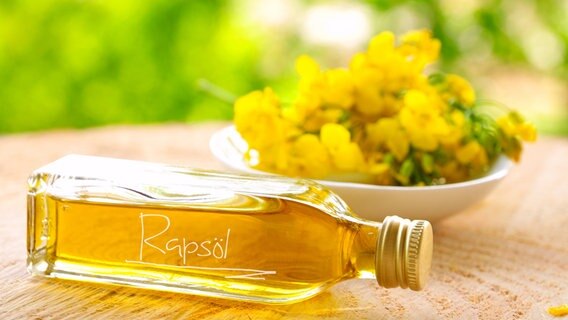 Eine  Flasche mit Rapsöl und Rapsblüten auf einem Holztisch. © Fotolia.com Foto: Kathleen Rekowski