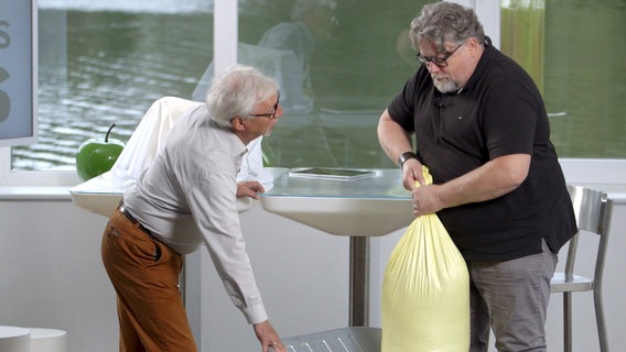 Ernährungs-Doc Jörn Klasen lässt seinen beleibten Patienten einen schweren Sack anheben. Ernährungs-Doc Jörn Klasen lässt seinen beleibten Patienten einen schweren Sack anheben. © NDR/Oliver Zydek