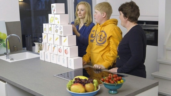 Ärztin baut zusammen mit jungem Patienten und seiner Mutter aus Würfeln die Ernährungs-Pyramide. © NDR 