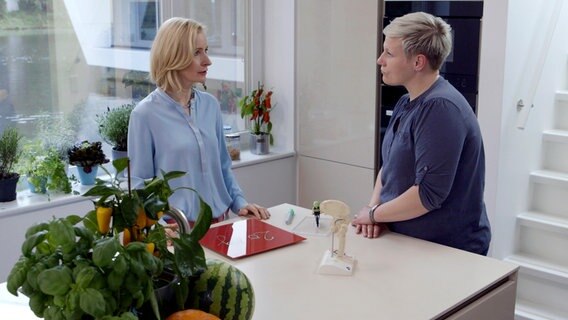Anne Fleck unterhält sich mit einer Patientin in der Hausboot-Küche, auf dem Tisch steht ein Hüftgelenk-Modell. Anne Fleck unterhält sich mit einer Patientin in der Hausboot-Küche, auf dem Tisch steht ein Hüftgelenk-Modell. © NDR/nonfictionplanet