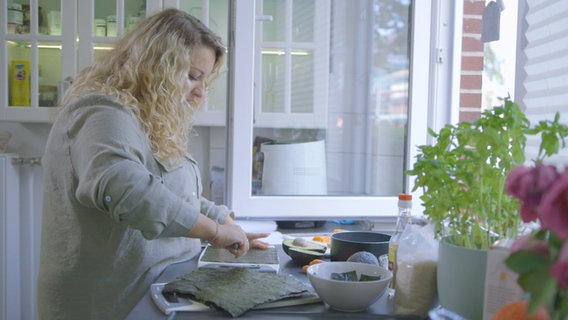Blonde Frau macht Sushi in ihrer Küche selbst. © NDR/nonfictionplanet/Matthias Wittkuhn 