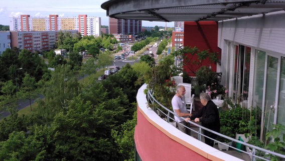 Filmautor Steffen Schneider steht mit dem ehemaligen Architekten Christoph Weinhold auf seinem Balkon mit Blick auf Lütten Klein. © ndr.de Foto: ndr.de