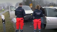 Zwei Personen vom Rettungsdienst Lüneburg sprechen mit einem Mann an einer Unfallstelle. © NDR 