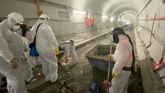Im Alten Elbtunnel wird die Fahrbahn aufgestemmt und saniert. Die Männer arbeiten unter Vollschutz, denn die alten Dichtungen enthalten giftiges Blei. © NDR/Björn Platz 