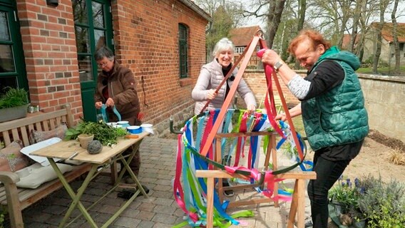 Aus Nachbarschaft wurde Freundschaft Ulrike, Petra und Ursel beim Gestalten eines Maikranzes für das erste Maifest in Karrenzin. (v.l.) Aus Nachbarschaft wurde Freundschaft Ulrike, Petra und Ursel beim Gestalten eines Maikranzes für das erste Maifest in Karrenzin. (v.l.) © NDR/Felix Weichbrodt