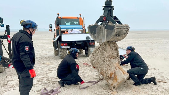Mitarbeiter des niedersächsischen Kampfmittelbeseitigungsdienstes bergen einen Torpedo-Gefechtskopf am Strand von Wangerooge. Mitarbeiter des niedersächsischen Kampfmittelbeseitigungsdienstes bergen einen Torpedo-Gefechtskopf am Strand von Wangerooge. © NDR/Bärbel Fening
