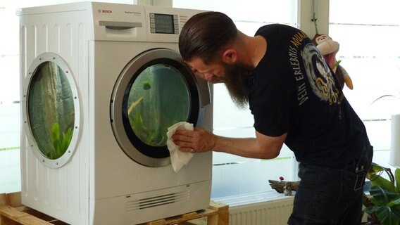Das Wichtigste für Daniel Reincke sind zufriedene Kunden - penibel putzt er die Scheiben des Waschmaschinen-Aquariums vor der Übergabe an eine Kinderpflegestätte. © NDR/Extra Vista 