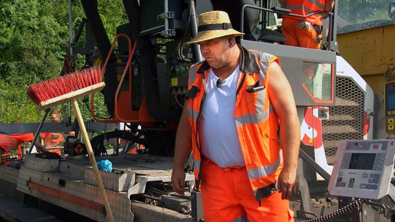 Michael Weinhold sorgt dafür, dass der 160 Grad heiße Asphalt auf die Autobahn 2 kommt. Er ist der Vorarbeiter des riesigen Fertiger-Zugs. © NDR/FILMBLICK Produktion Hannover GbR/Stefan Radüg 