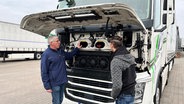 Einweisung für den neuen Fahrer: Max (r.) hat gerade erst sein Vorstellungsgespräch gehabt und muss schon auf die erste Fahrt nach Ulm. Vorher gibt es eine Einweisung in den Lkw vom Fuhrparkleiter der Spedition Grüßing aus Westerstede. © NDR/LEMON8/Thorsten Schöntaube 