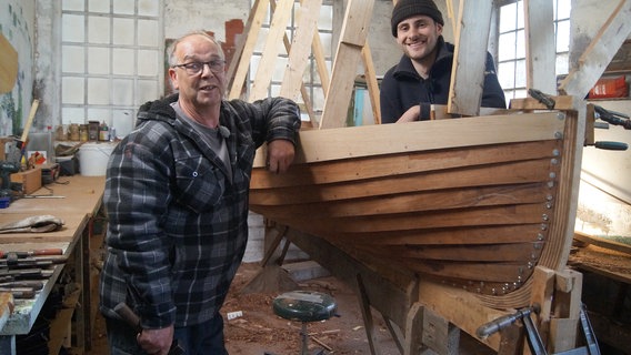 In Freiburg an der Elbe arbeitet Bootsbauer Elia Wirth (rechts) noch traditionell mit Holz. Rainer Hatecke (links) führt den Werftbetrieb in fünfter Generation. In Freiburg an der Elbe arbeitet Bootsbauer Elia Wirth (rechts) noch traditionell mit Holz. Rainer Hatecke (links) führt den Werftbetrieb in fünfter Generation. © NDR/Milena Schwoge