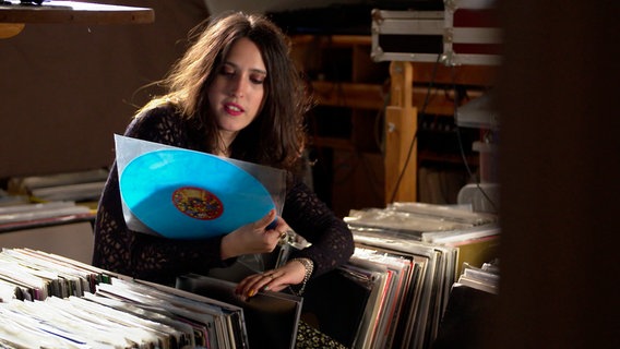 D-Jane Helena Hauff sieht sich in einem Plattenladen eine Vinylscheibe an. © NDR 