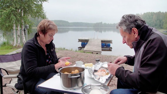 Rena und Gustav sitzen an einem See und essen Abendessen. © NDR/Sonja Kättner-Neumann 