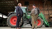 Streitschlichter Christian Teppe und Bauernsohn Jürgen Meinecke stehen sich gegenüber. Hinter ihnen parkt ein Trecker. © NDR 