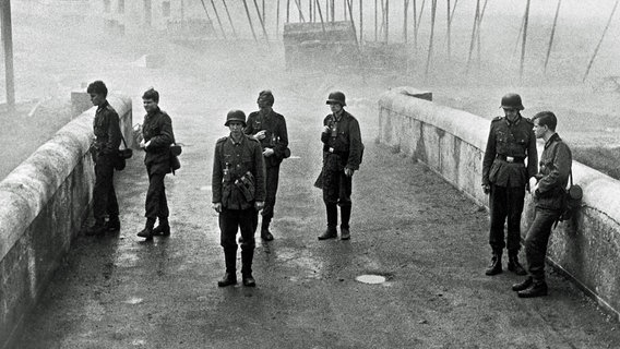 Kurz vor Ende des Zweiten Weltkriegs erhalten die unbedarften Oberschüler Hans Scholten (Folker Bohnet), Albert Mutz (Fritz Wepper), Walter Forst (Michael Hinz), Jürgen Borchert (Frank Glaubrecht), Klaus Hager (Volker Lechtenbrink), Sigi Bernhard (Günther Hoffmann) und Karl Horber (Karl Michael Balzer) den militärisch sinnlosen Auftrag, eine Brücke in ihrem Heimatort zu verteidigen. © ARD Degeto 