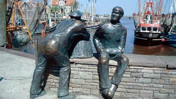 Im Hafen der ostfriesischen Ortschaft Neuharlingersiel stehen zwei Bronzestatuen, die einen jungen und einen alten Fischer darstellen  