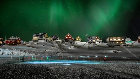 Polarlicht über Dorf auf Grönland. Das Fußballspiel an der Küste Grönlands wird auch vom Polarlicht erhellt. Satellitenbilder zeigen uns das Phänomen noch einmal ganz anders. © NDR/BBC 