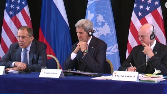 Sergej Lawrow sitzt neben John Kerry auf dem Podium.  