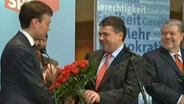 Sigmar Gabriel übergibt einen Blumenstrauß.  