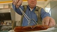 Mann serviert eine Grillwurst  