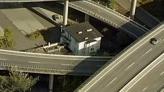 Ein Haus steht alleine mitten in einem Autobahnkreuz  