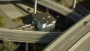 Ein Haus steht alleine mitten in einem Autobahnkreuz  