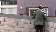 Ein Mann steht vor einer Mauer. © NDR 