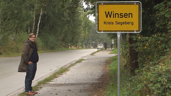 NDR Reporter Henning Nasse steht neben dem Ortsschild von Winsen im Kreis Segeberg.  Foto: Screenshot