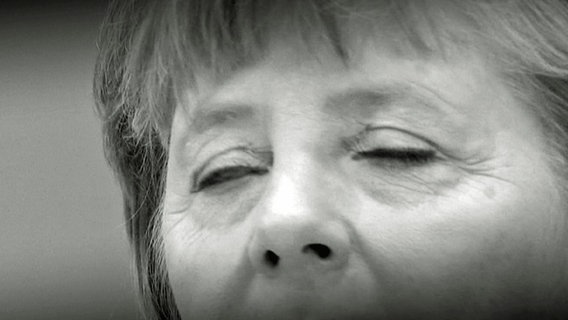 Die geschlossenen Augen von Angela Merkel in einer Nahaufnahme in Schwarz-Weiß. © NDR Foto: Screenshot