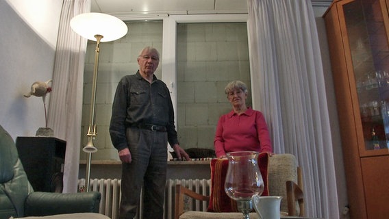 Ehepaar Quedenbaum steht in seinem Wohnzimmer vor dem zugemauerten Fenster. © NDR Foto: Screenshot