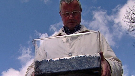 Ein Mann hält eine durchsichtige Kiste mit Regenwürmern. © NDR Foto: Screenshot