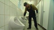 Ein Mann reinigt eine Toilette.  