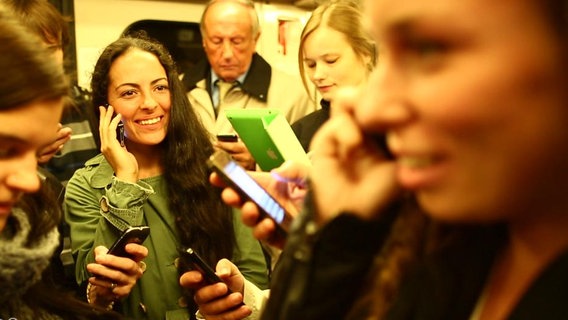 Eine Gruppe junger Menschen spielt oder telefoniert mit Smartphones.  