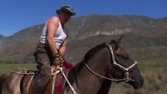 Russlands Präsident Wladimir Putin steigt auf ein Pferd.  