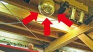 Drei rote Pfeile zeigen auf eine Disco-Kugel an der Decke einer hohen Halle. © NDR Foto: Screenshot