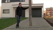 Ein Mann lehnt an einer Laterne, die inmitten seiner Garagenauffahrt steht. © NDR Foto: Screenshot