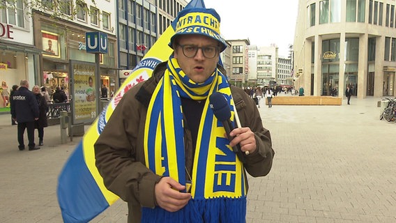 Henning Nasse macht in Fankleidung von Eintracht Braunschweig einen Aufsager. © NDR Foto: Screenshot