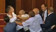 Mehrere Abgeordnete des ukrainischen Parlaments schlagen einen anderen und drängen ihn ab.  