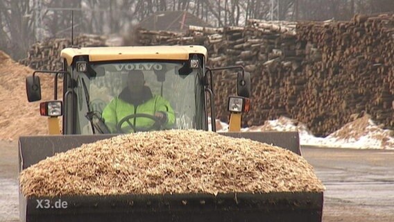 Ein mit Holzspähnen beladener Bagger.  