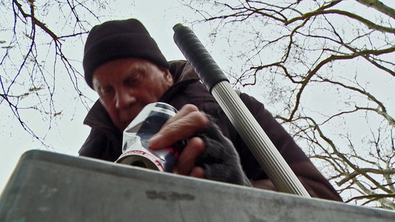 Ein alter Mann holt eine Getränkedose aus einem Mülleimer. © NDR Foto: Screenshot