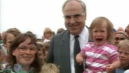 Eine Familie stellt sich für ein Foto neben Helmut Kohl.  