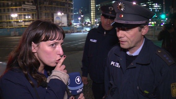 Caro Korneli bedeutet einem Polizisten leise zu sein. © NDR 