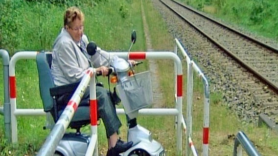 Frau im Rollstuhl vor einem Bahnübergang © NDR 
