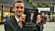 Tobias Schlegl hält sein neuestes Buch hoch: "Das AKW Krümmel. Gesammelte Störfälle." © NDR 