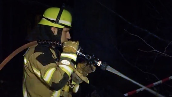 Ein Feuerwehrmann in Delmenhorst löscht einen Brand. © NDR 